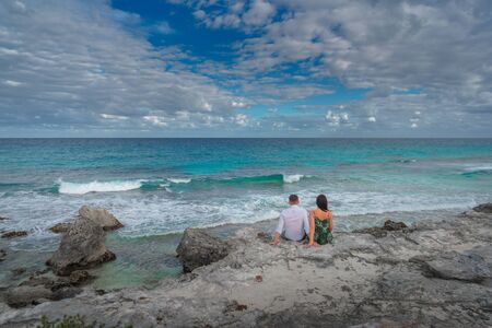 young couple sitting on the rocks in the water not far from the beachの写真素材