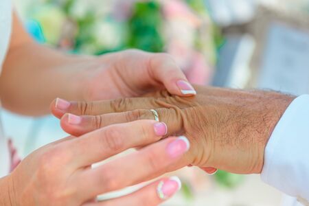 Hands of the newlyweds at the wedding ceremony of dressing the wedding rings, hands close-up.の写真素材
