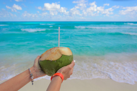 Coconut with drink in hand against the backdrop of the Caribbean