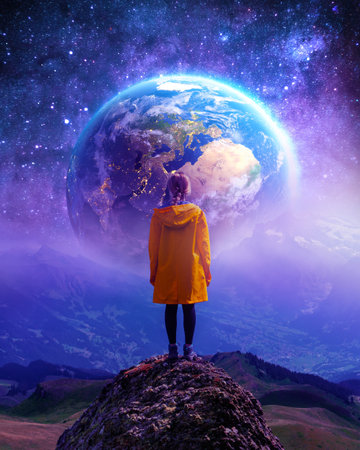 The girl stands with her back and looks at the starry sky and the planet earthの写真素材