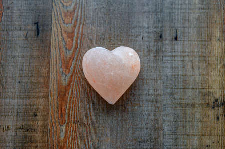 Pink stone heart with rock stones in background. Symbol of love.の写真素材
