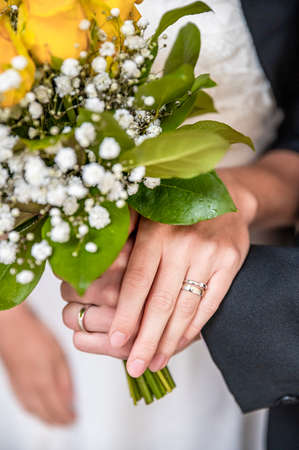 Detail of hands together of wife and groom with wedding flower.の写真素材