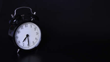 Close up image of old black vintage alarm clock. Time management and deadline urgency concept. Seven o'clock and thirty minutesの写真素材