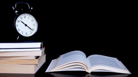 Back to school background with alarm clock, books and open book.