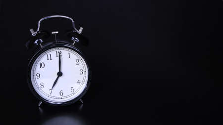 Close up image of old black vintage alarm clock. Time management and deadline urgency concept. Seven o'clockの写真素材
