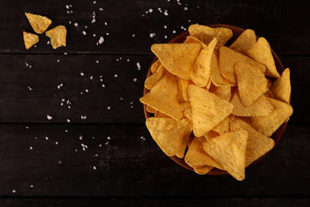 Mexican nachos in Wooden Bowl tortilla chips with chilli pepper and salt, Black wooden Background,...