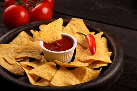 Mexican nachos in Wooden Bowl tortilla chips with chilli sauce, pepper, tomatoes, salsa and cheese...