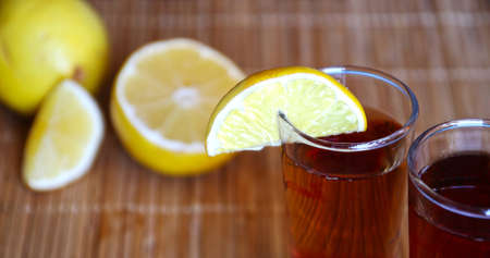 Close up shot glasses of ice green lemon tea with lemon slices on wooden backgroundの写真素材