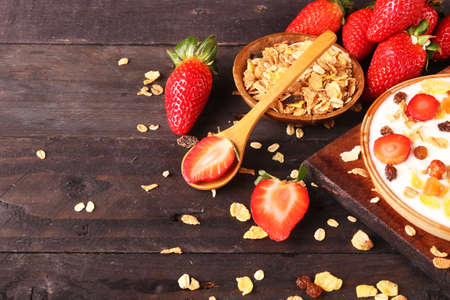 Bowl of yogurt with strawberries and granola muesli, over a white wood background.の写真素材