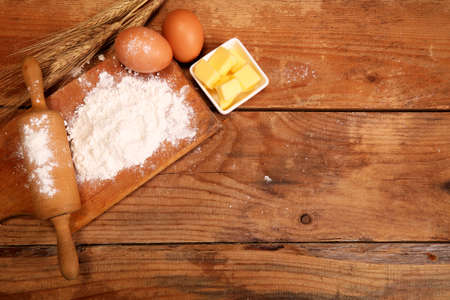 Kitchen rolling pin, wooden bowl with flour on rustic wooden background and butter for making croissant on table.の写真素材