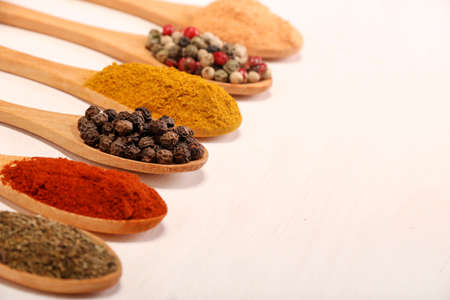 Group of indian spices and herbs difference ware in wooden spoons on white background with normal...