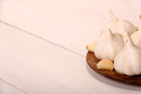 Garlic Cloves and Bulb in vintage wooden plate on white wooden rustic table.の写真素材