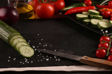 Healthy food. Vegetables on a black plate and stone cutting board and wooden black table background....