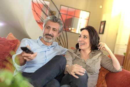 Happy middle-age couple watching a film togetherの写真素材
