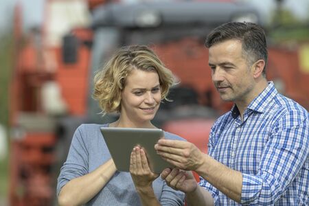 Couple of Farmer analyses the harvesting in a field over a digital tabletの写真素材