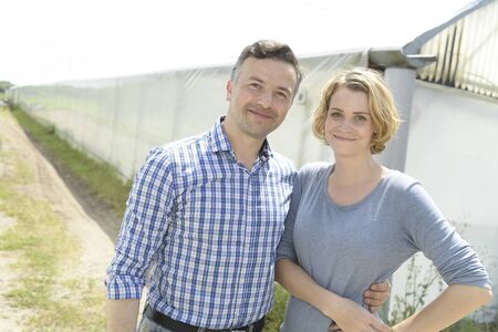 Young farming couple in front of  the greenhouseの写真素材