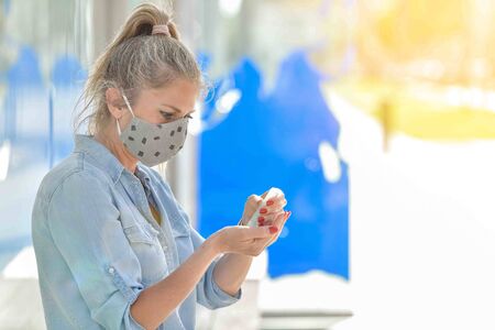 Portrait of a woman wearing protective mask against coronavirus and applying hydroalcoholic protective lotion on her handsの写真素材