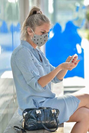 Portrait of a woman wearing protective mask against coronavirus and applying hydroalcoholic protective lotion on her handsの写真素材
