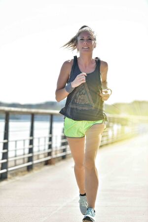 Female runner during her running session along a river in the cityの写真素材