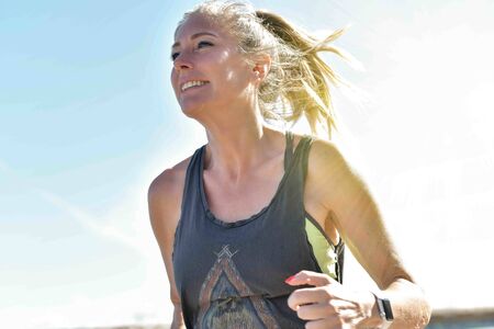 Female jogger during her running session along a river in the city