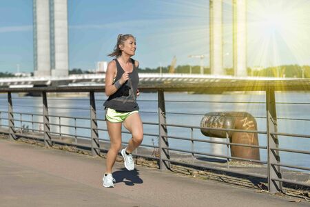 Female jogger during her running session along a river in the cityの写真素材
