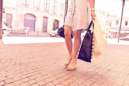 View of female legs walking on the street with bagsの写真素材
