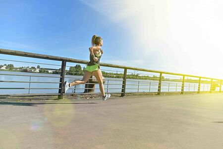 Athletic, middle age female  during her running cession along the riverの写真素材