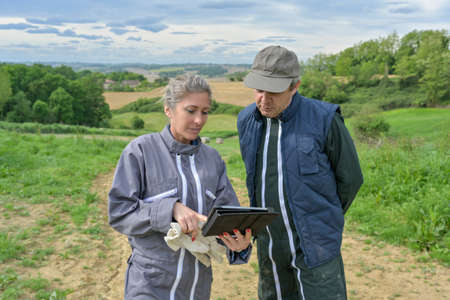 Farmer couple studying the environment on a digital tablet to define the best conditions for their plantationsの写真素材