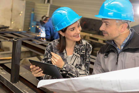 Workers discussion with digital tablet and industrial drawing