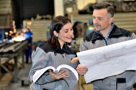 Two workers are having fun in the factory while they are reading some documentsの写真素材