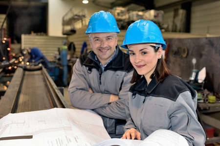 Confident man and woman are smiling at the camera in the factoryの写真素材