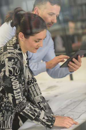Concentrated female worker is working with a blueprint in officeの写真素材