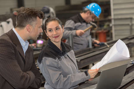 Female worker uses a blueprint to reassure her managerの写真素材