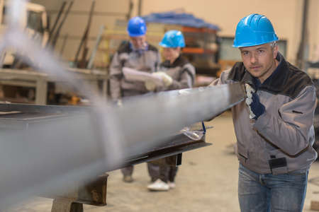 Concentrated male worker positioning a metal bar in metal factoryの写真素材