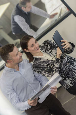 Happy co-workers are doing a selfie with a tablet at workの写真素材