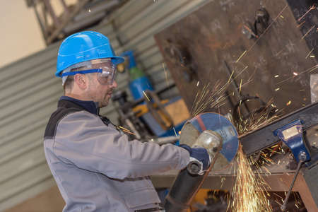 Male worker wearing protective cloths cutting a metal bar with circular sawの写真素材