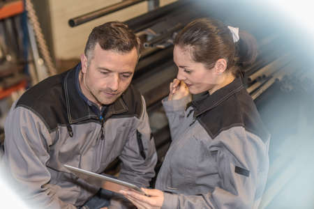 Female apprentice showing manager table in metal factoryの写真素材