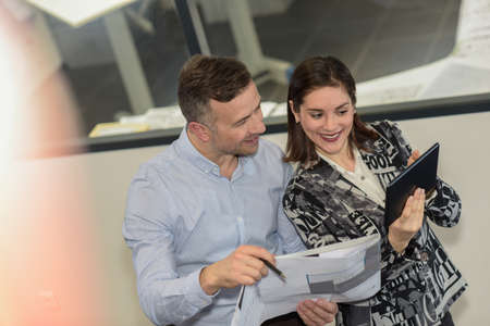 Happy woman is showing her male colleague positive results on a tabletの写真素材