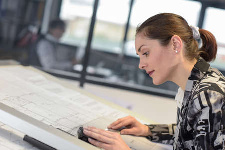 Woman works on a drawing in an engineering firmの写真素材