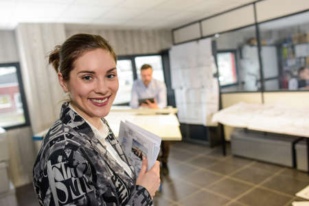 Happy female worker holding a stack of paper in her hadsの写真素材