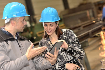 Positive female engineer is point at tablet in the factoryの写真素材