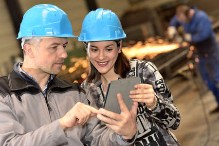 Workers in a steel industry checking the production method on a digital tablet.の写真素材