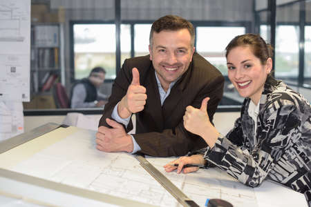 Happy co-workers are given thumb-up to the cameraの写真素材
