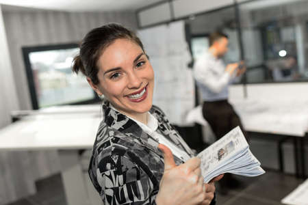 Positive female businesswoman is giving a thumb-up in officeの写真素材