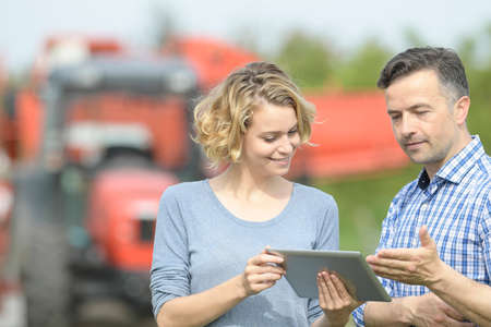 Couple of Farmer analyzes the harvesting in a field over a digital tabletの写真素材