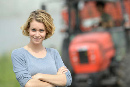 Smiling female farmer in front of his tractorの写真素材