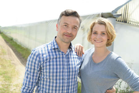 Young farming couple in front of the greenhouseの写真素材