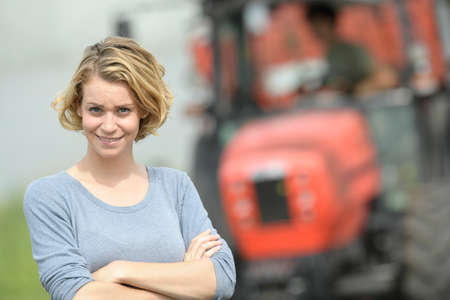 Smiling female farmer in front of his tractorの写真素材