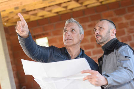 Architect father helping mature son with the construction of a new house