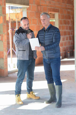 Architect and contractor looking at plans on a building siteの写真素材